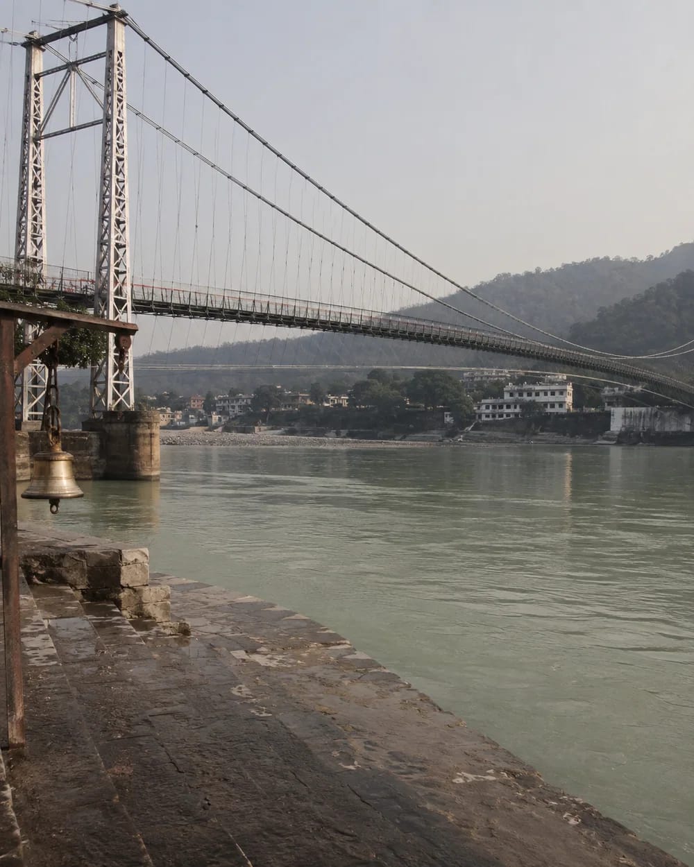 A suspension footbridge crossing the Ganga above stone steps in Rishikesh