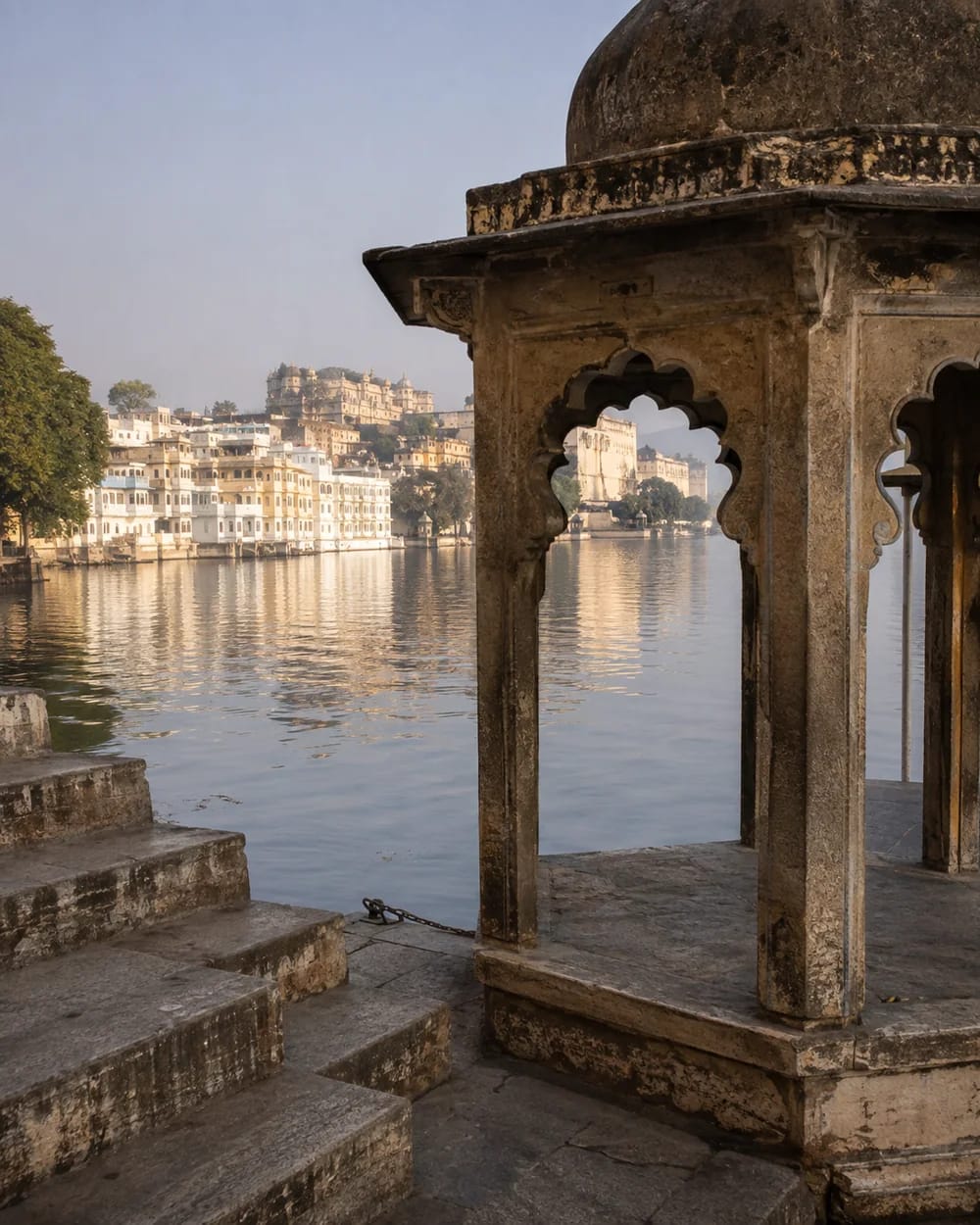 A weathered stone chhatri and ghat overlooking Lake Pichola in Udaipur